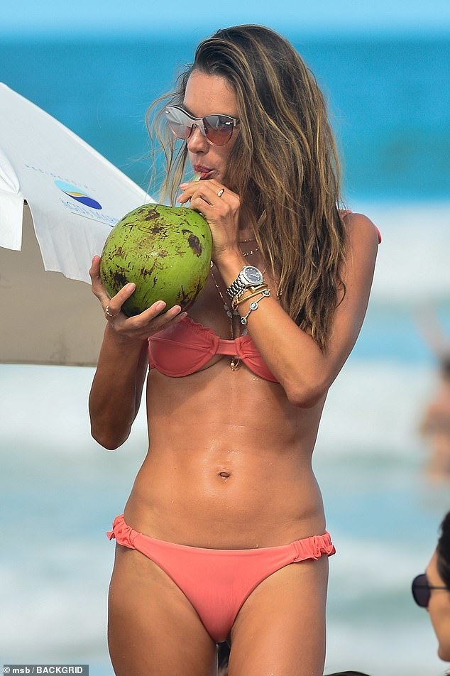 Модель Alessandra Ambrosio на фото в розовом купальнике с кокосом.