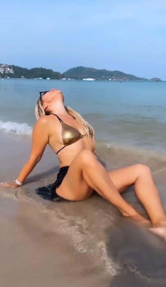 Тут она на пляже в золотом лифчике от купальника.